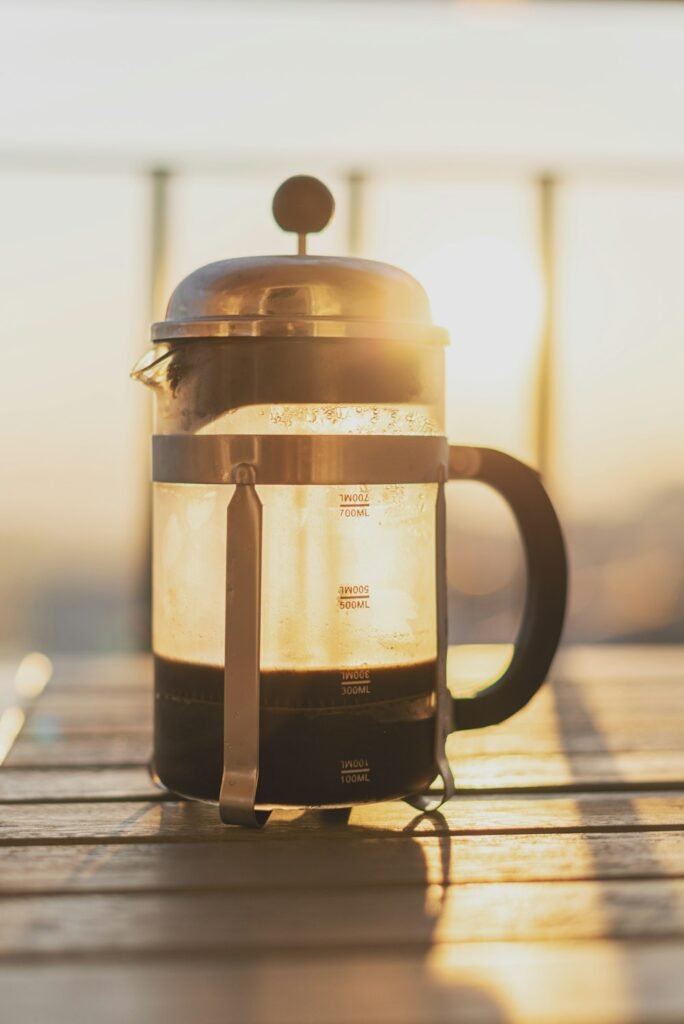Cafetière à piston remplie de café, éclairée par la lumière du soir