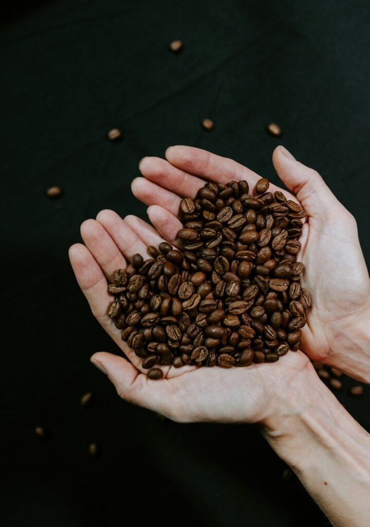 Deux mains en coupe remplies de grains de café torréfiés